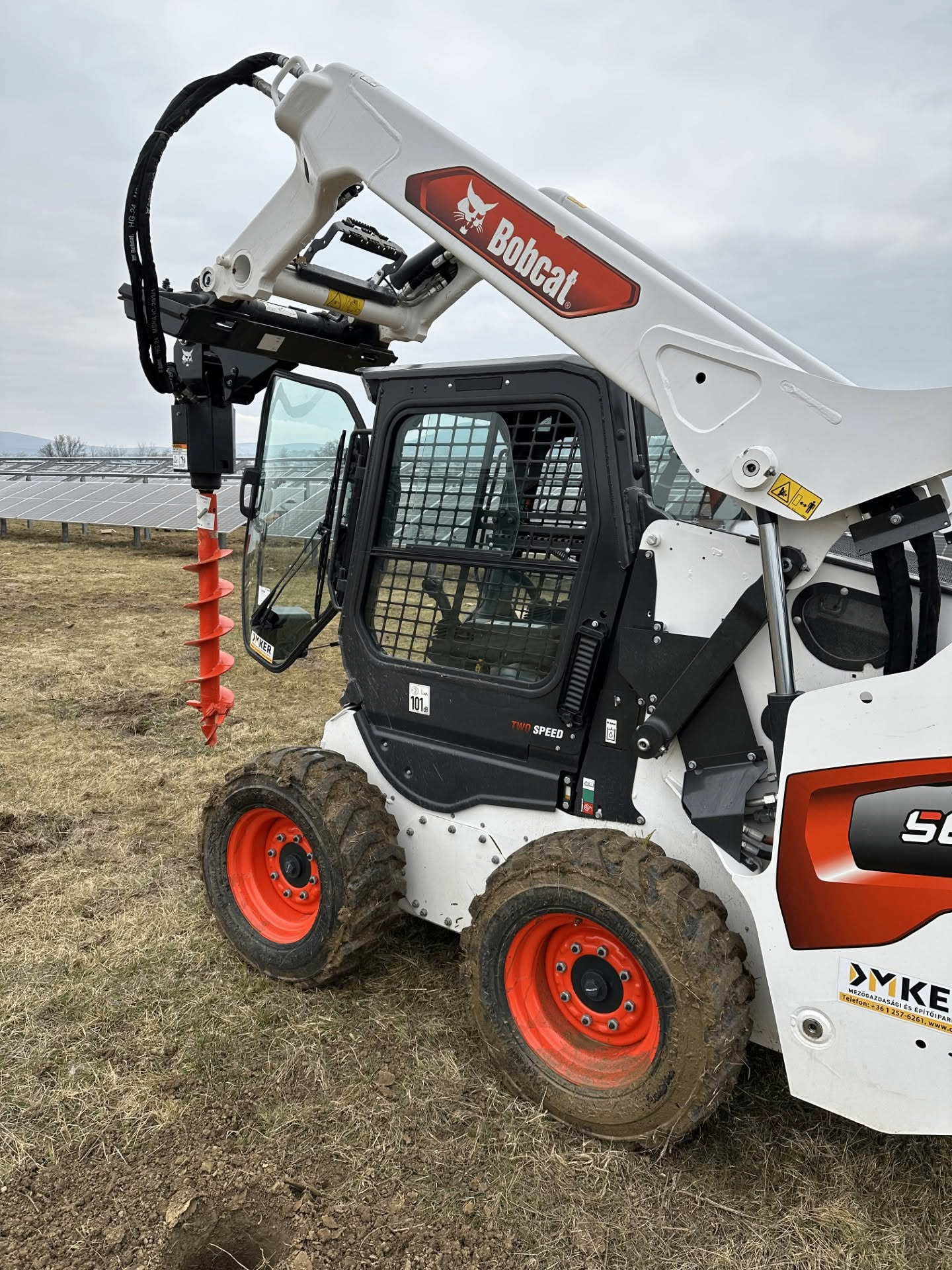 Bobcat rakodógép földfúró adapterrel egy napelemparkban